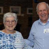 Man and woman pose for photo, both wearing blue